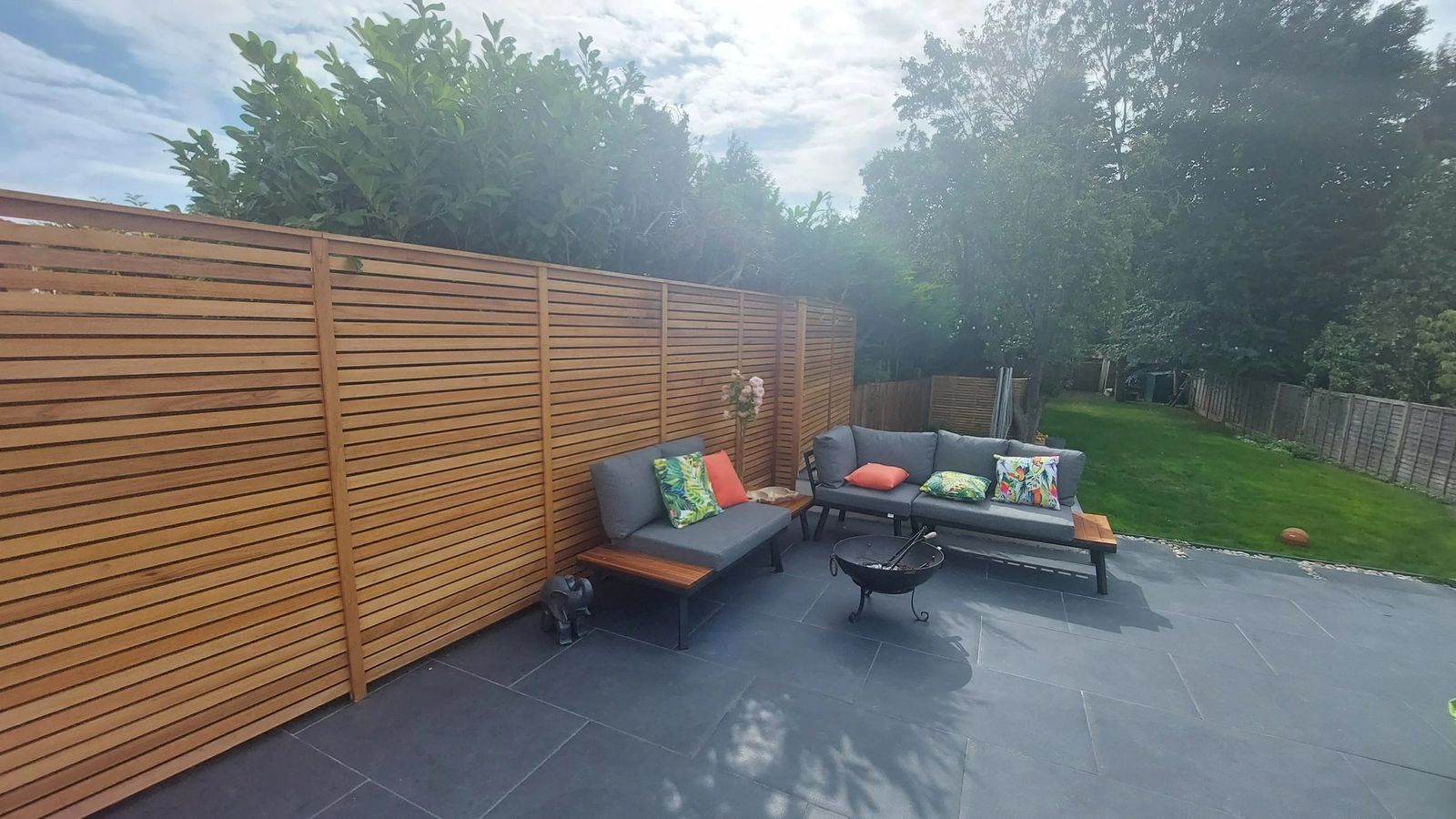 Large dark grey paved terrace enclosed by tall horizontal slatted cedar screens